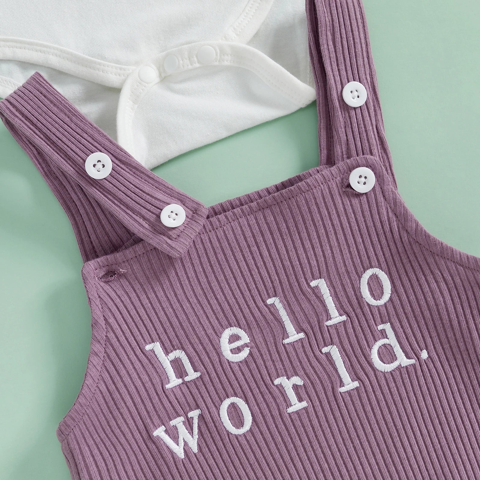 Close-up of baby girl romper with flutter sleeves and purple ribbed overall