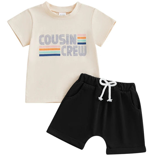 Flat lay of cream Cousin Crew t-shirt and black shorts – matching baby set