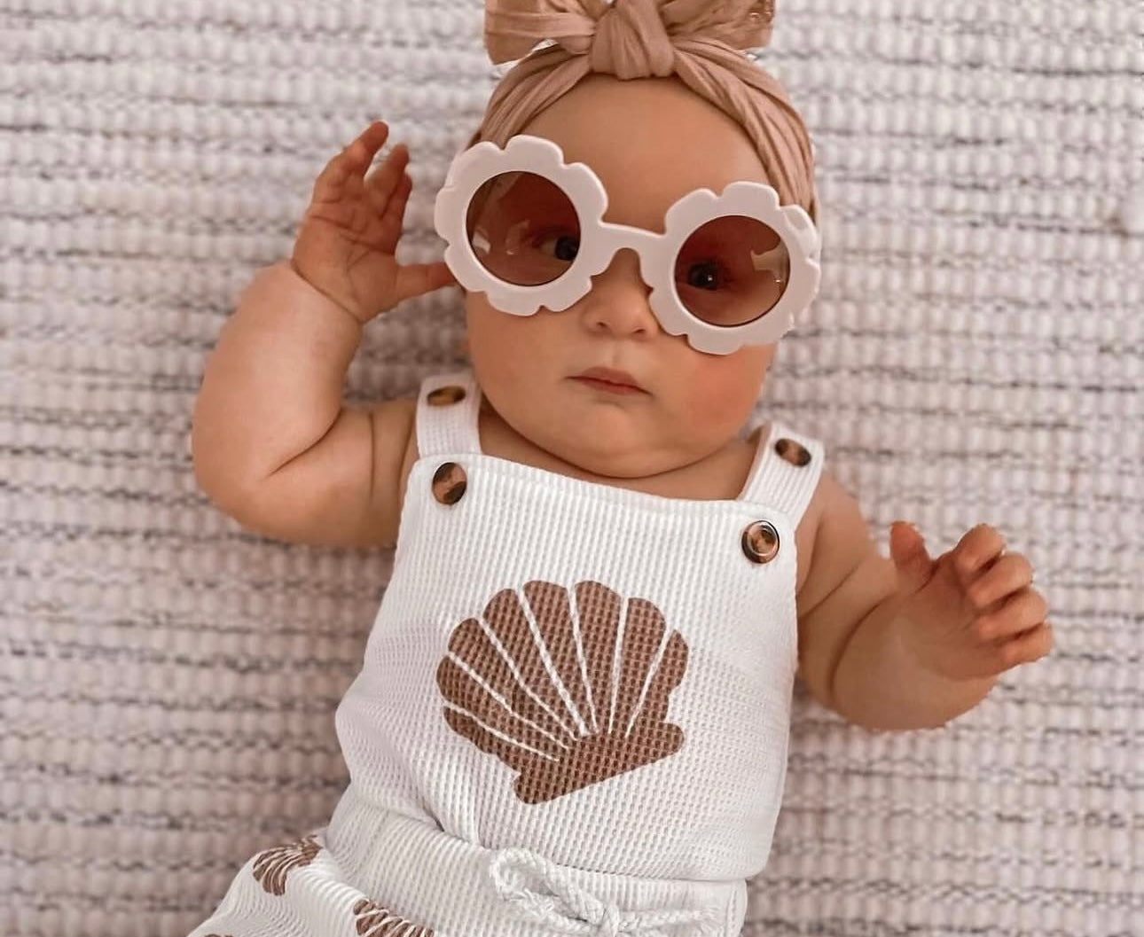 A baby girl wearing Pipp & Lola brand baby clothing with a cute pair of sunglasses